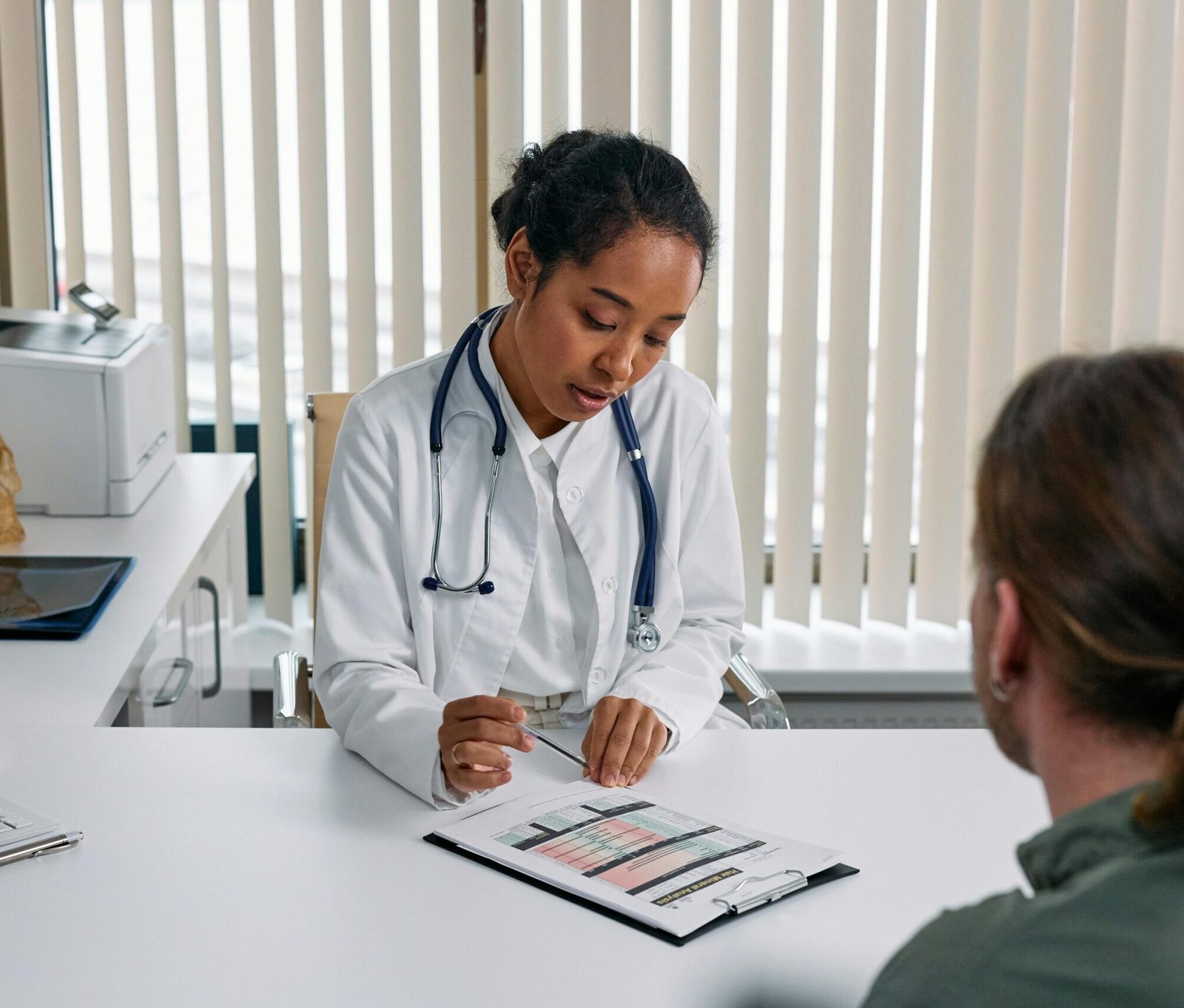 A doctor consulting with a patient in an office, discussing a medical chart.
